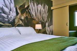 a bedroom with a bed with a painting of plants at The Palms Luxury Suites in Swakopmund