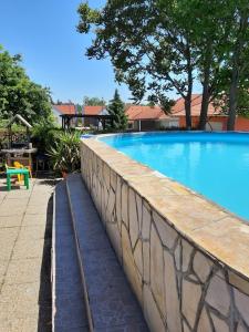 a large blue swimming pool with a stone wall at Balaton Beach Gyenesdiás in Gyenesdiás