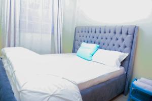 a bedroom with a bed with a blue headboard at A&T Luxury Homestays in Kisii
