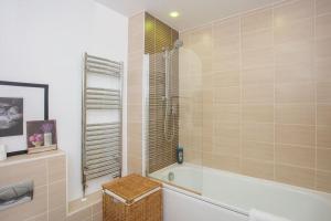 a bathroom with a tub and a glass shower at Unique & Welcoming 2BD Flat in Limehouse in London