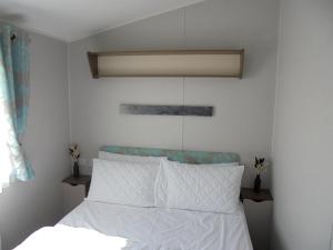 a bedroom with a bed with a white comforter at Kingfisher : Seasons:- 8 Berth, Central Heated, Close to site shop in Ingoldmells