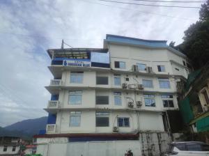 een hoog wit gebouw met een balkon bij Hotel Obsidian Blue in Itānagar