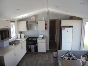 a small kitchen with a stove and a refrigerator at Kingfisher : Seasons:- 8 Berth, Central Heated, Close to site shop in Ingoldmells