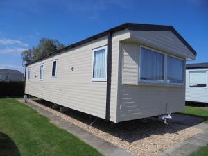 a small white trailer parked in a yard at Kingfisher : Seasons:- 8 Berth, Central Heated, Close to site shop in Ingoldmells
