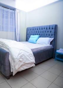 a bed with a blue headboard in a room at A&T Luxury Homestays in Kisii
