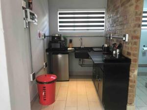 a kitchen with a black counter and a red trash can at Red Lotus Studio Pta East-No Loadshedding in Pretoria