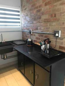 a black counter with a sink and a brick wall at Red Lotus Studio Pta East-No Loadshedding in Pretoria