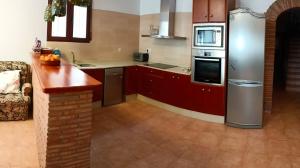 a kitchen with red cabinets and a stainless steel refrigerator at La cerrada in El Collado +6 photos