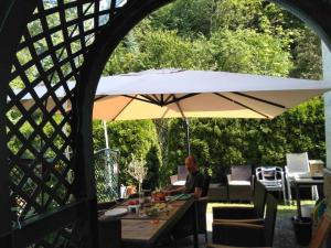 a man sitting at a table under an umbrella at Zu Hause am Bach in Aggsbach