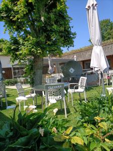 une terrasse avec une table, des chaises et un parasol dans l'établissement Auberge du Vieux Tour Le Manoir, à Canapville