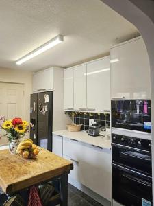 uma cozinha com uma mesa e um frigorífico preto em Tortoise Haven Bicester- Comfortable quiet home with garden em Stratton Audley