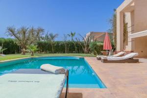 una piscina con 2 tumbonas y una casa en fleur de marrakech, en Marrakech