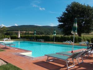 una gran piscina con sillas y sombrillas en Bazzani Apartments, en Pieve a Scuola