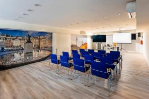 une salle de conférence avec des chaises bleues et un écran dans l'établissement Hotel Zielonki, à Zielonki
