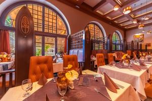 a dining room with tables and chairs and windows at Botaniq Room in Gyula