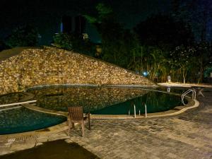 una sedia seduta di notte di fronte a una piscina di The Roar Resort a Ramnagar