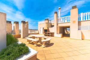 a patio with a table and benches on a building at 2-Bed Apartment with rooftop pool in Formentera del Segura
