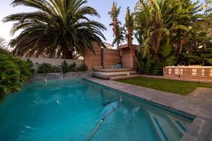 a swimming pool in front of a house with palm trees at Amara Lincoln - 100m From Camps Bay Beach in Cape Town