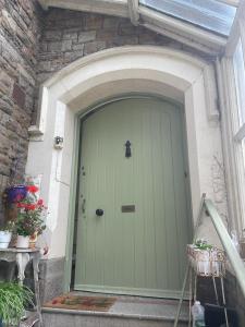 uma porta verde de uma casa com uma parede de pedra em Westbrook-Homestay em Swansea