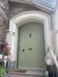 a green door of a house with a stone wall at Westbrook-Homestay in Swansea