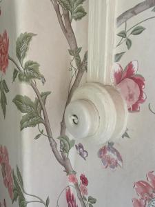 a wall with a flowery wallpaper with a light on it at Westbrook-Homestay in Swansea