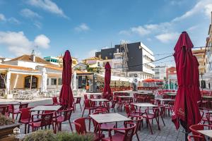 a group of tables and chairs with red umbrellas at The Pateo Beach Apartment - Santa Cruz in Santa Cruz