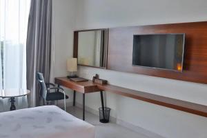 Habitación de hotel con escritorio y TV. en Pakons Prime Hotel, en Tangerang