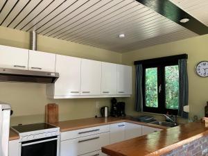 a kitchen with white cabinets and a clock on the ceiling at Bungalow Rochehaut au calme in Rochehaut