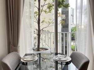 a table with two chairs and a tree in a window at Thonglor Modern studio condo in Khlong Toei