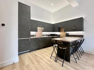 a kitchen with black cabinets and a table with stools at Fountain Apartment No 2 with Free Parking in York