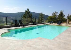 a swimming pool with chairs and blue water at Locanda del Buon Cammino in Chiusi della Verna