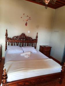 a bedroom with a large wooden bed with white sheets at Hospedagem Serra da Lua in Alter do Chao