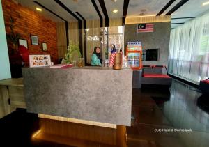 a woman standing behind a counter in a restaurant at Cute Hotel & Dorms Ipoh in Ipoh