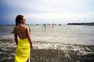 een vrouw in een gele jurk op het strand bij Villa Cha Cha Chaolao Beach Resort in Chao Lao Beach