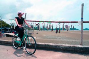 Eine Frau, die neben einem Haufen Fische Fahrrad fährt. in der Unterkunft Villa Cha Cha Chaolao Beach Resort in Chao Lao Beach