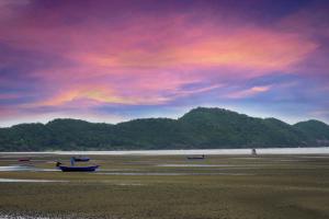 three boats sitting on a beach under a cloudy sky at Villa Cha Cha Chaolao Beach Resort in Chao Lao Beach