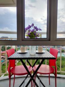 a table with two chairs and a vase of flowers on a window at Tagaytay Condo Staycation in Iruhin