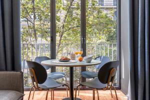 mesa y sillas en una habitación con ventana grande en Aspasios Diagonal Art, en Barcelona