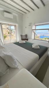 ミコノス・シティにあるAlia Luxury Villa Mykonosの白いベッドルーム(大型ベッド1台、窓2つ付)