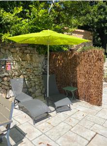 two chairs and an umbrella on a patio at Tiny House au coeur des Combes in Seillans