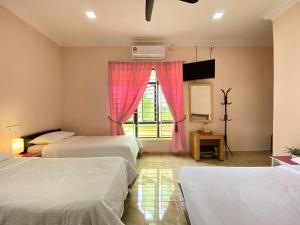 una camera d'albergo con due letti e una finestra di Besut Guesthouse a Kampung Kuala Besut