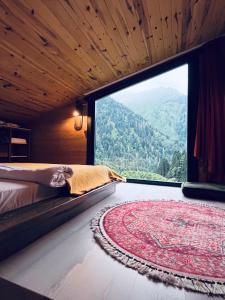um quarto com uma grande janela com uma cama e um tapete em Kukudi House em Ayder Yaylasi