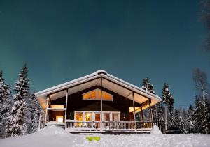 a house in the snow at night with snow at Napapiirin Järvilomat in Rovaniemi