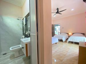 a hotel room with two beds and a bathroom at Besut Guesthouse in Kuala Besut