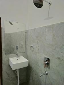 a bathroom with a white sink and a shower at Motel Ilika in Bilāspur