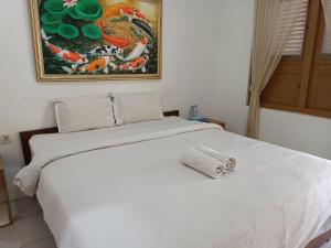 a white bed in a bedroom with a painting on the wall at Hotel Maerakatja Yogyakarta in Jetis