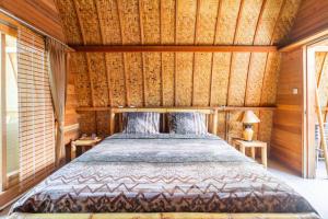 a bedroom with a bed in a room with wooden walls at Djamezz Lumbung in Gili Air