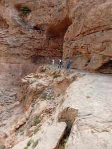 un grupo de personas de pie al lado de un acantilado en Maison D'hôtes Chez Bassou Agoudal en Agoudal