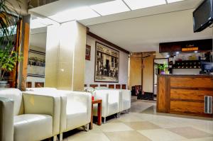 una sala da pranzo con sedie bianche e un bar di Bell Inn a Leskovac