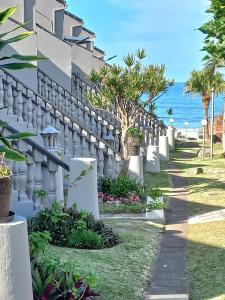 Une clôture blanche avec des arbres et l'océan en arrière-plan dans l'établissement Uvongo cabanas, à Margate